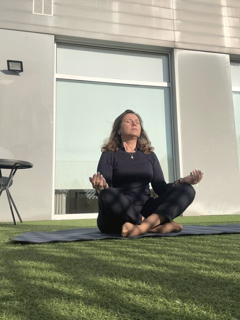 Isabel da Fonseca sentada na relva, em meditação, com luz natural suave